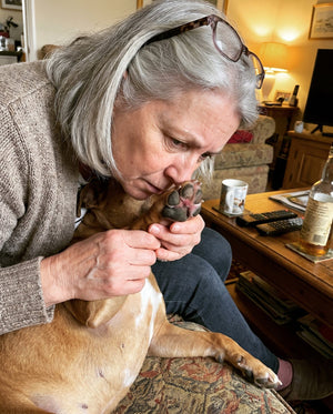 Una dueña oliéndole las almohadillas de las patas a su perro